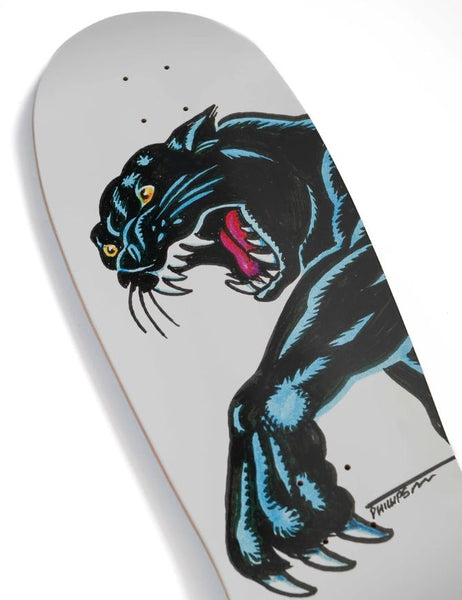 A close-up of a skateboard deck featuring a stylized black panther illustration with blue shading, yellow eyes, and a pink tongue on a light gray background.