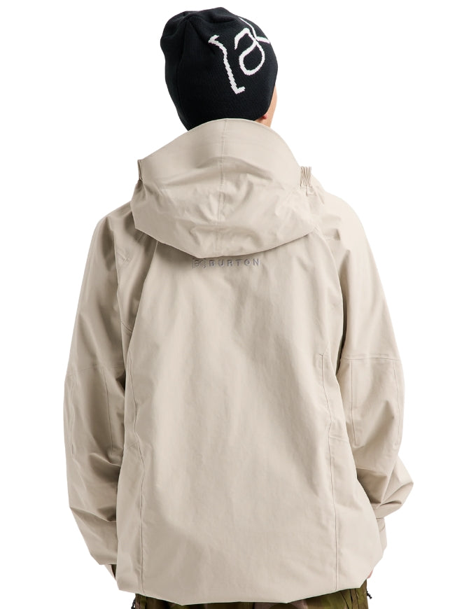 A person shown from the back wearing a light beige hooded jacket and a black beanie with a white graphic, photographed against a plain white background.