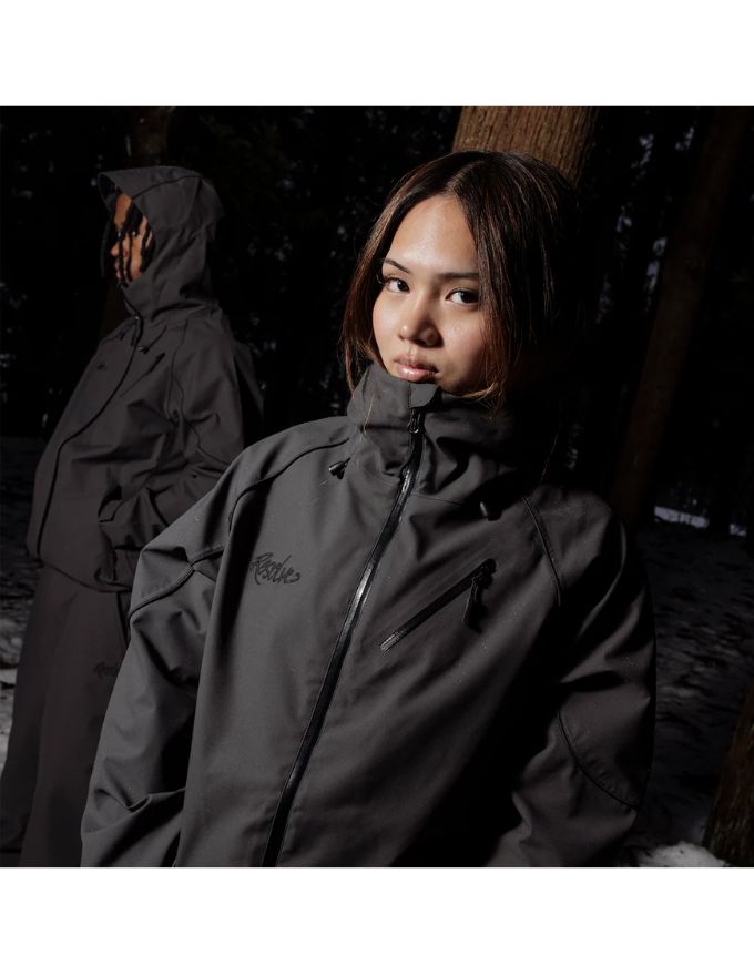 Person wearing a dark raincoat with a hood in a forest setting