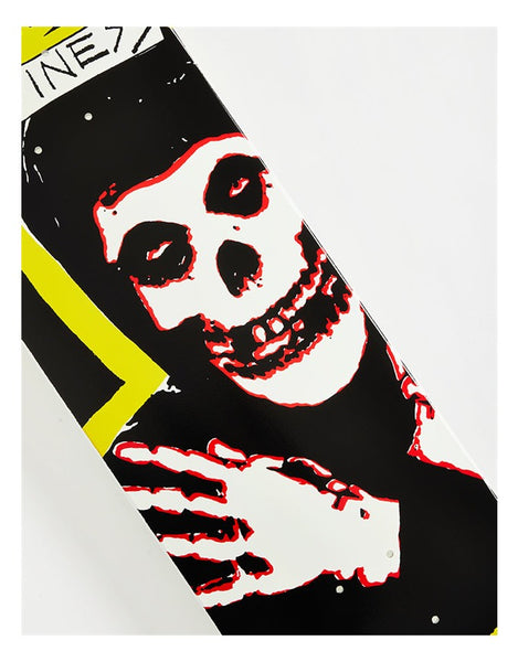 A close-up of a skateboard deck featuring a stylized skull graphic in white with red outlines, a black background, and a bright yellow accent stripe. Part of the text 'INE77' is visible at the top left.