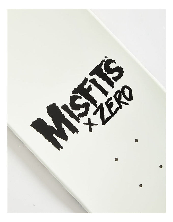 Close-up of a white skateboard deck featuring a black 'MISFITS x ZERO' graphic and grip tape dots, photographed on a light background.